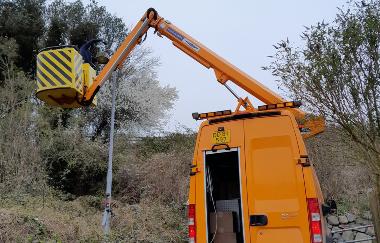 Orange liftbil med medarbejder der udskrifter vejbelysning.